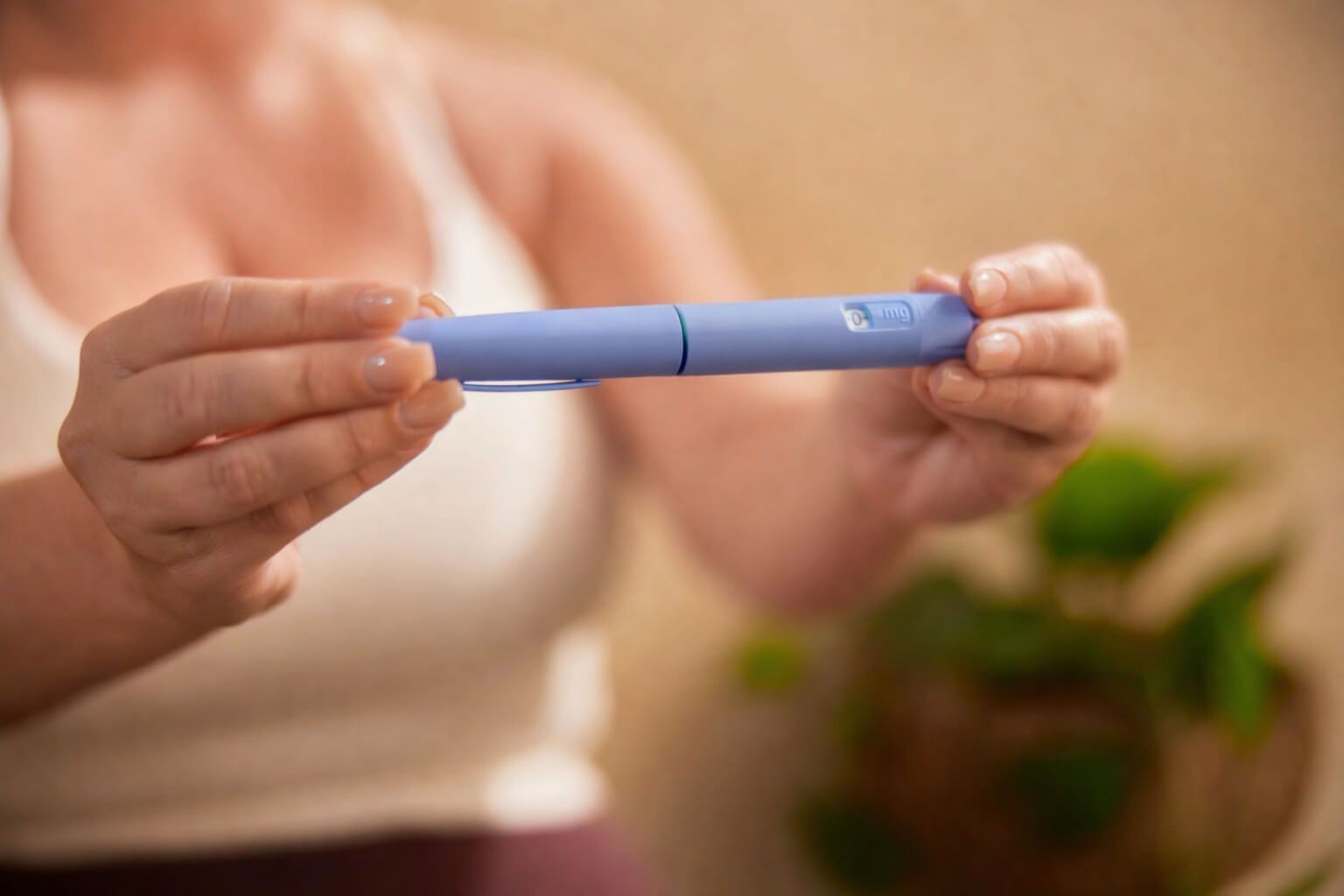 Close-up of hands holding a blue medical auto-injector device.