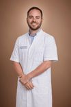 Smiling male doctor in a white medical coat with folded arms.