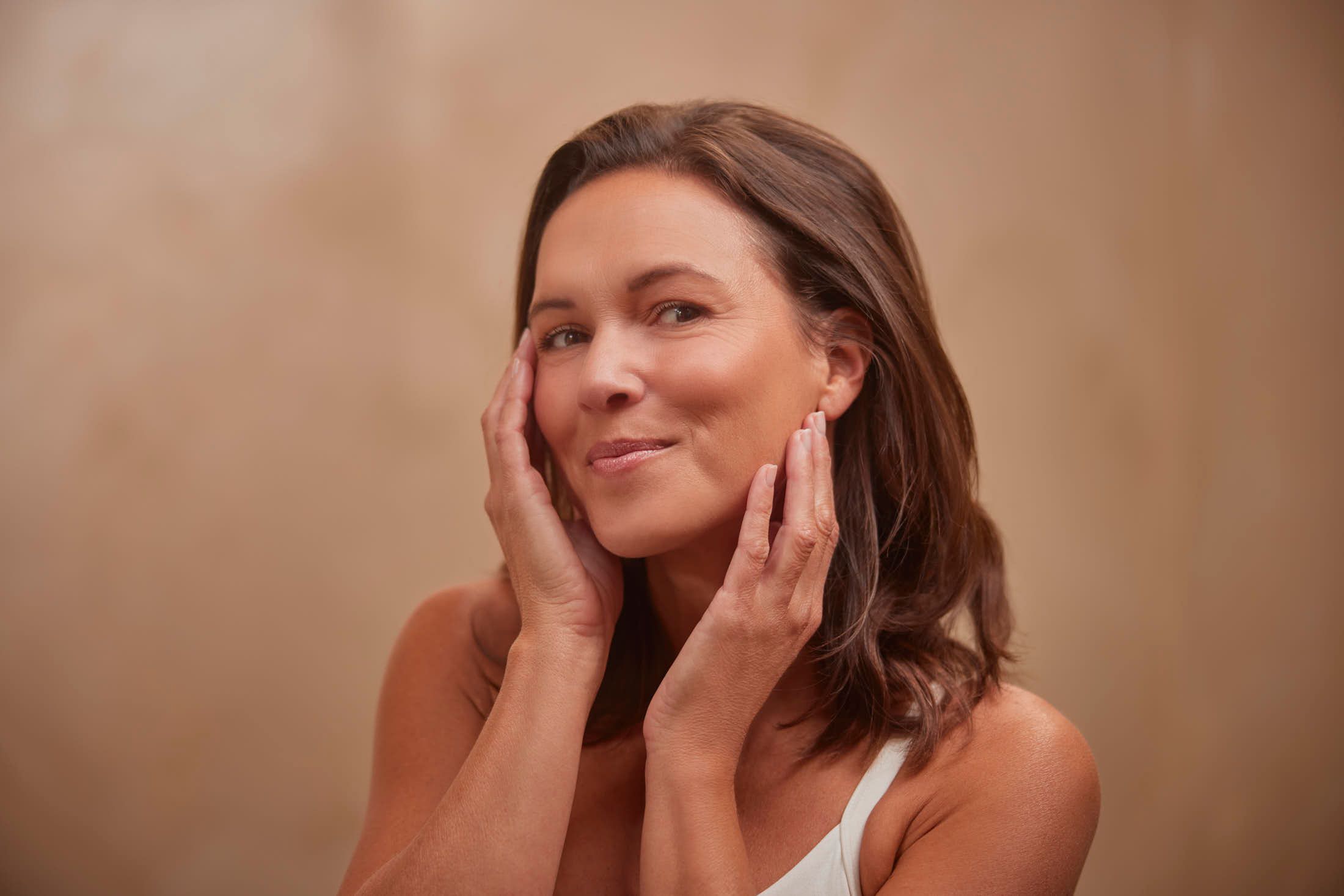 Client met stralende huid raakt wangen aan na filler behandeling bij The Body Clinic