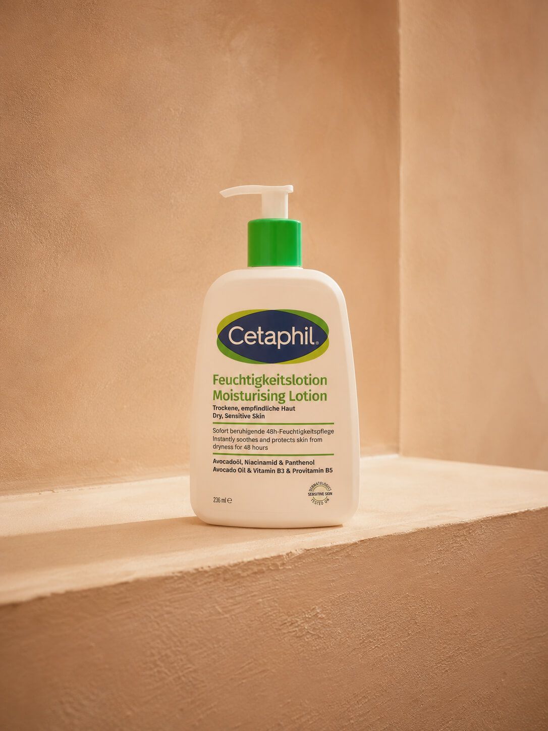 White Cetaphil moisturizing lotion bottle with a green pump on a beige ledge.