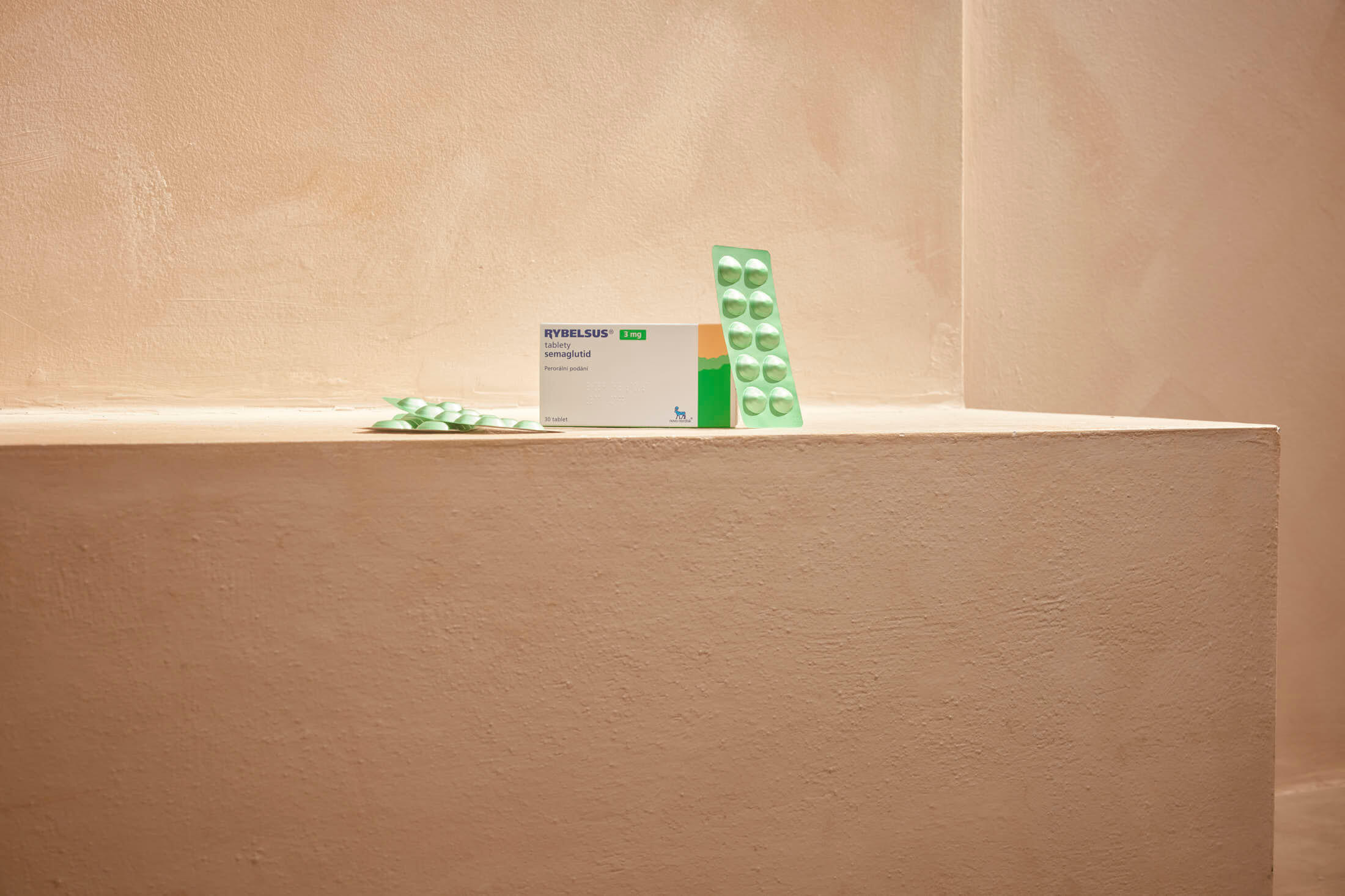 A box of Ibuprofen 200mg tablets sits next to green blister packs on a beige surface.