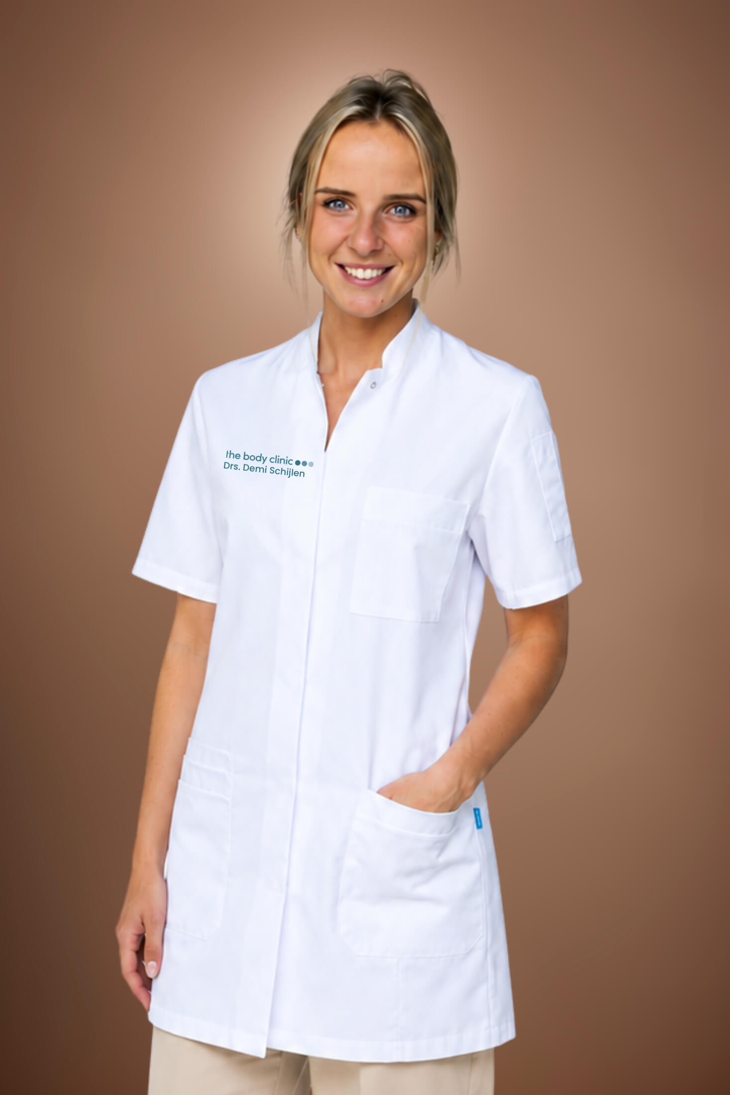 Smiling woman in white medical coat with hands in pockets.