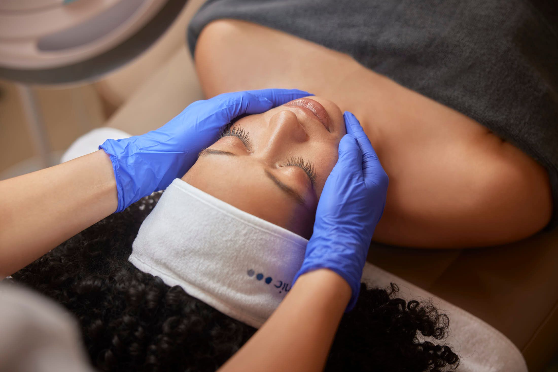Huidtherapeut voert lasertherapie tegen acne en acnelittekens uit bij client bij The Body Clinic