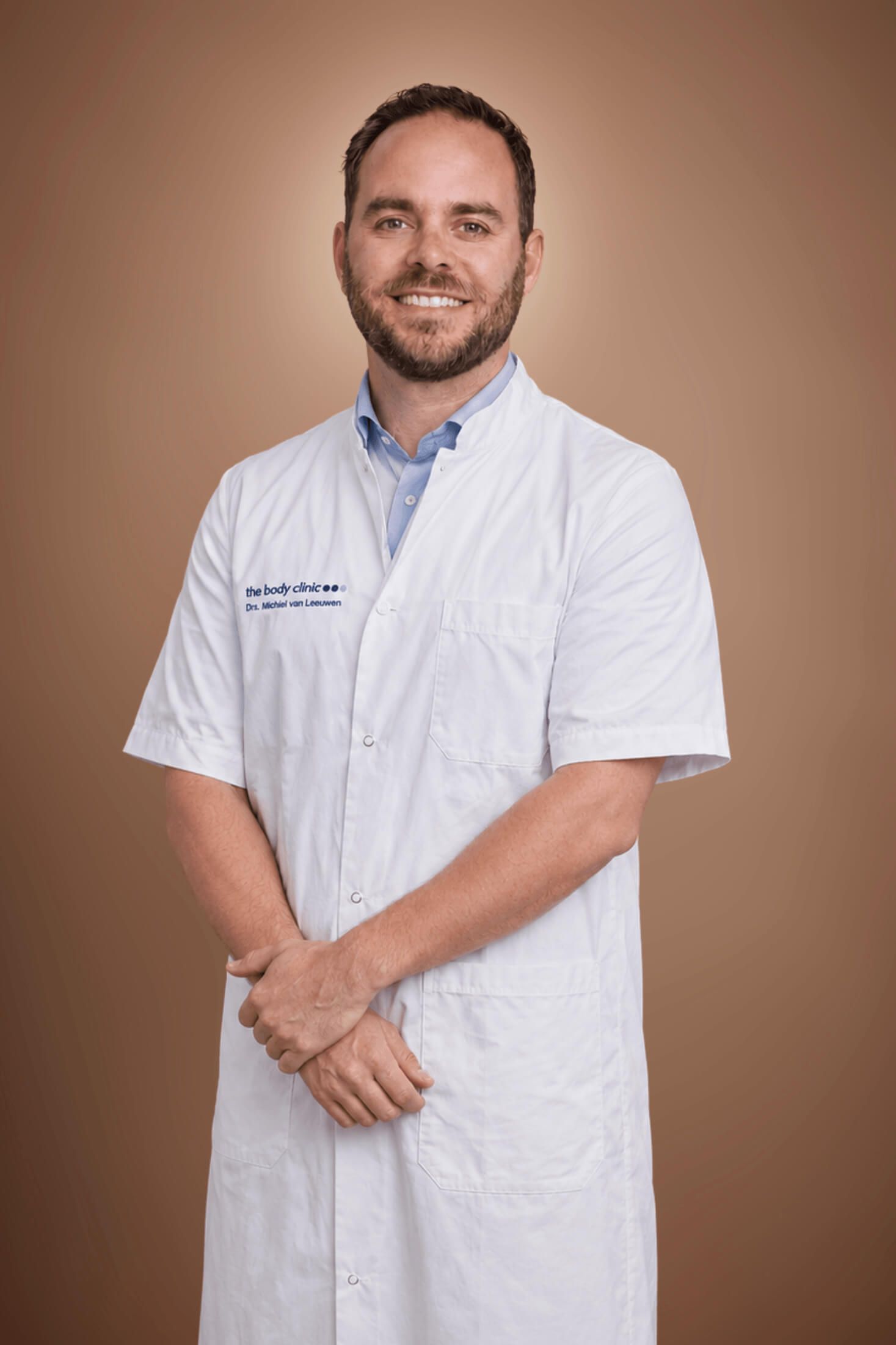 Smiling male doctor in a white medical coat with folded arms.