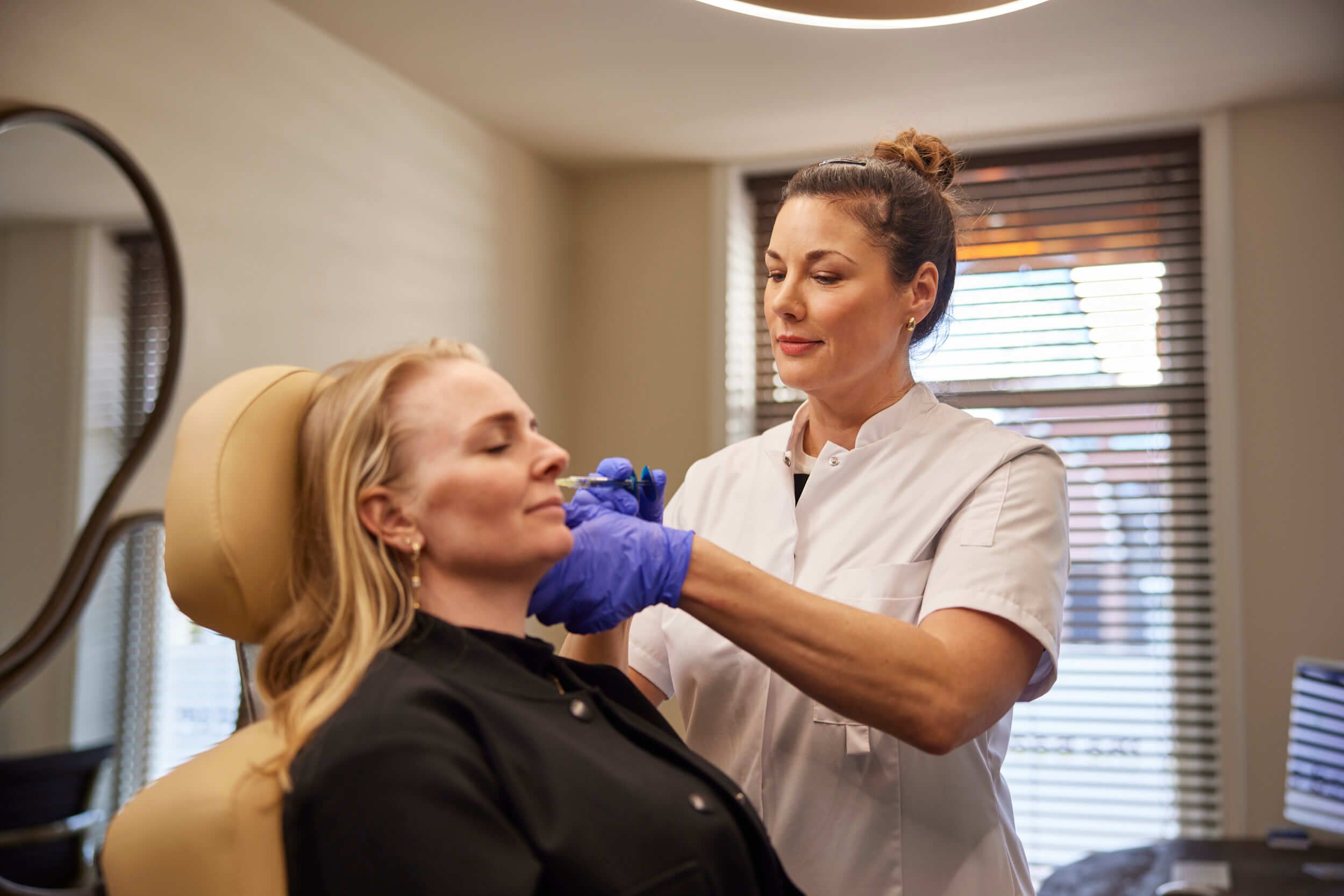 Cosmetisch arts voert neuslippenplooi filler behandeling met client bij The Body Clinic