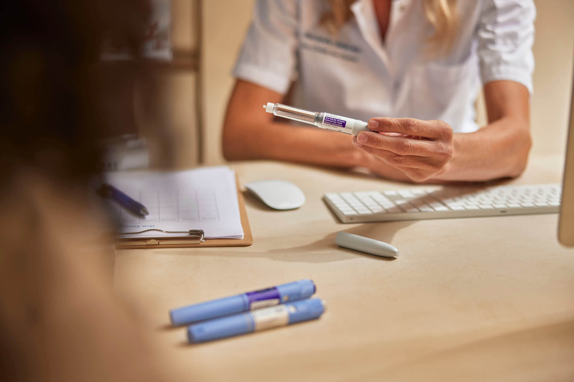 Healthcare professional explains how to use an insulin pen to a patient during a consultation.