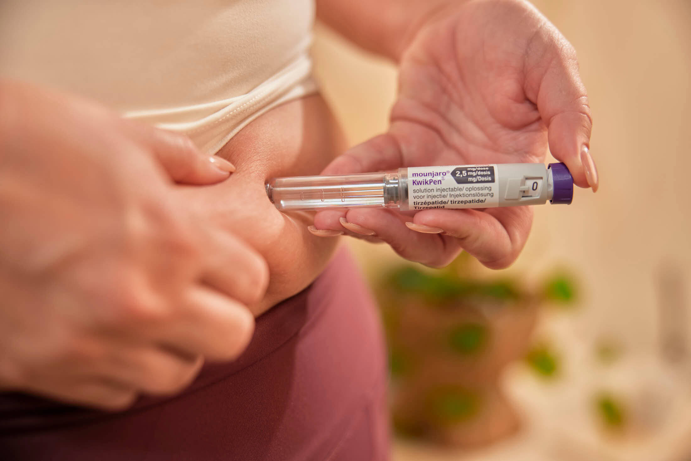 A person holds an insulin pen, preparing to self-inject into their abdomen.