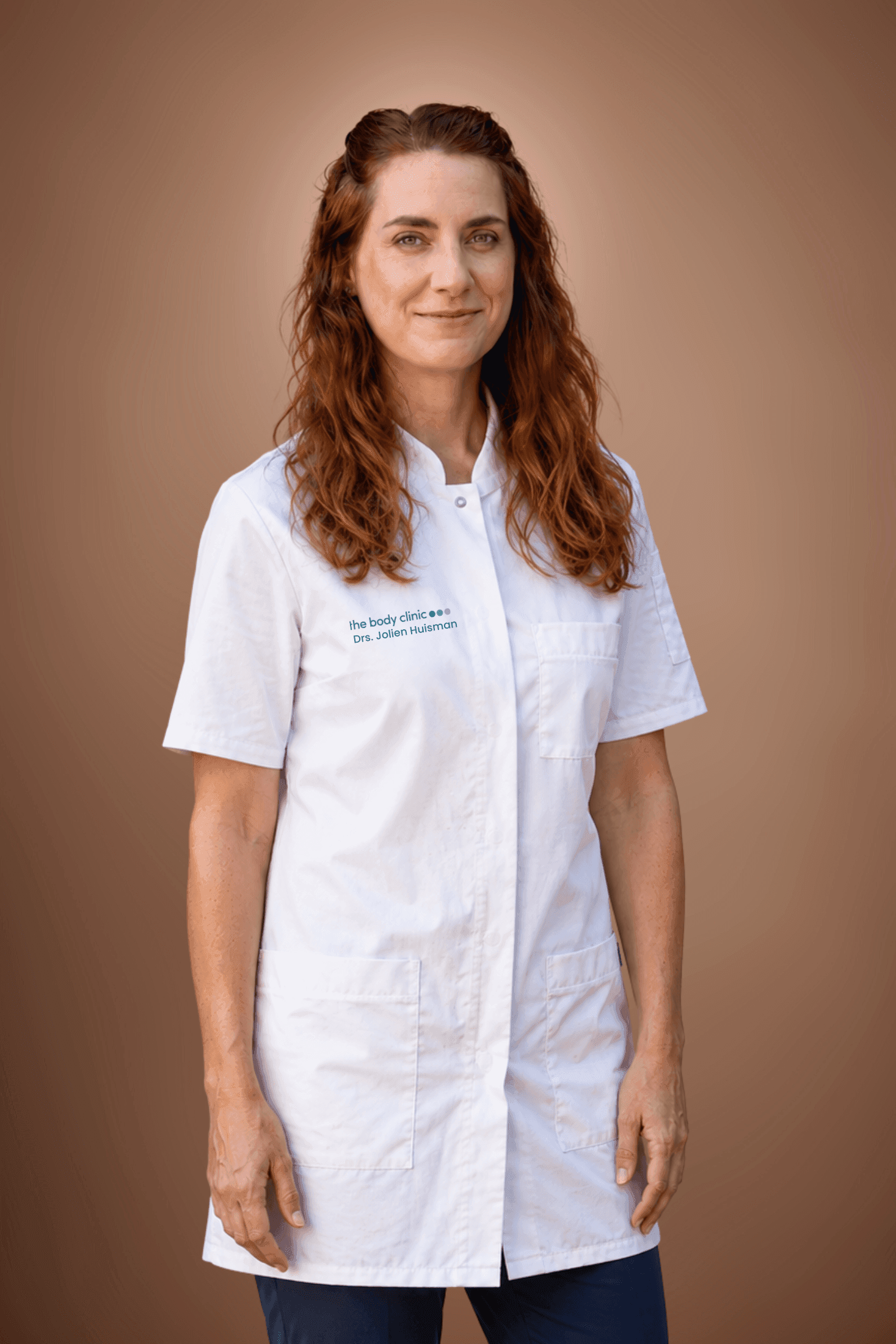 Professional woman with red hair in white lab coat smiles gently.