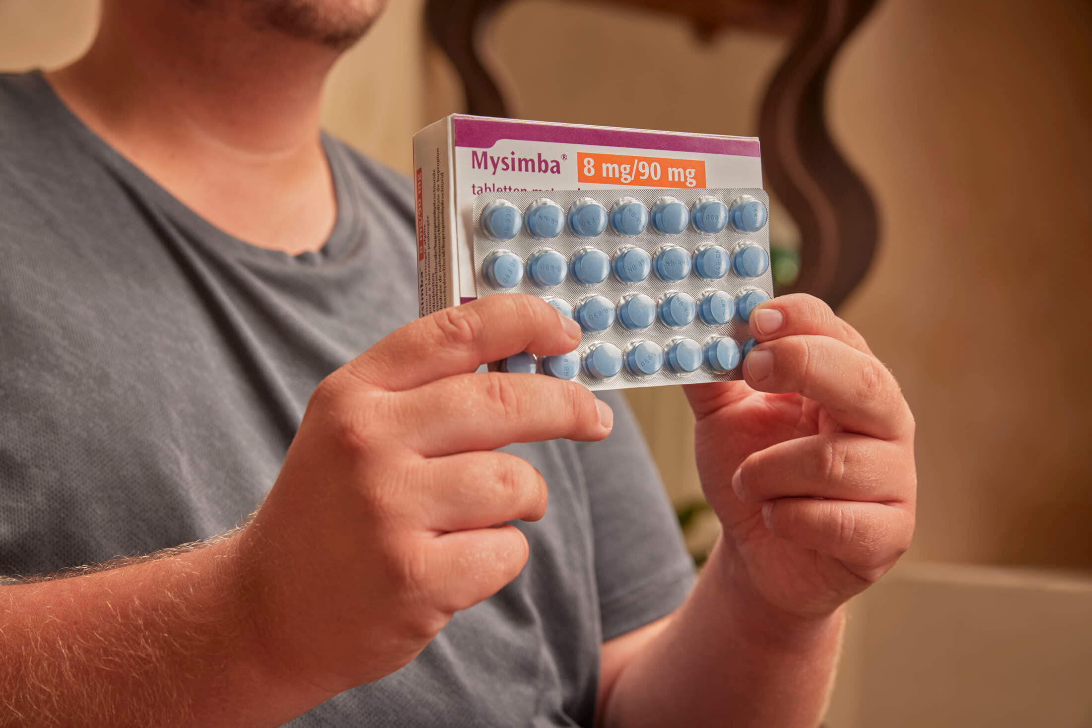 A person holds a blister pack of blue heart-shaped pills labeled "Viagra" and "Legrux."