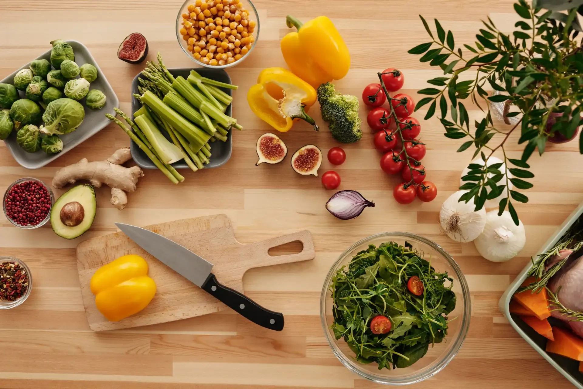 Fresh vegetables, a knife, and ingredients are neatly arranged on a wooden kitchen counter.