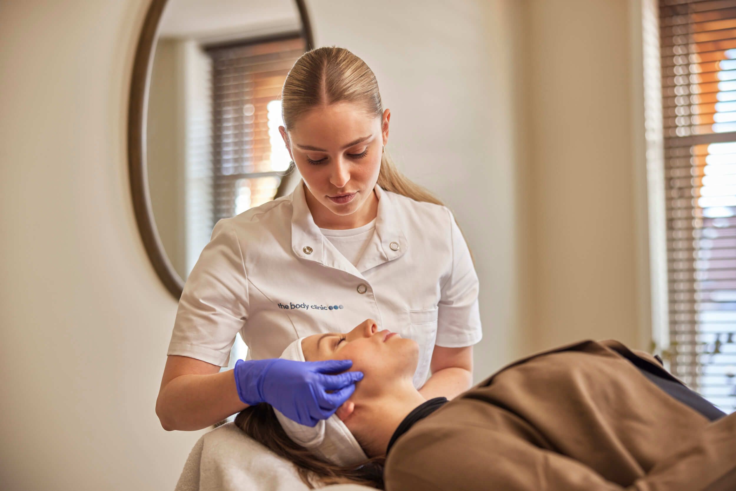 Huidtherapeut voert gezichtsbehandeling uit op cliënt bij The Body Clinic