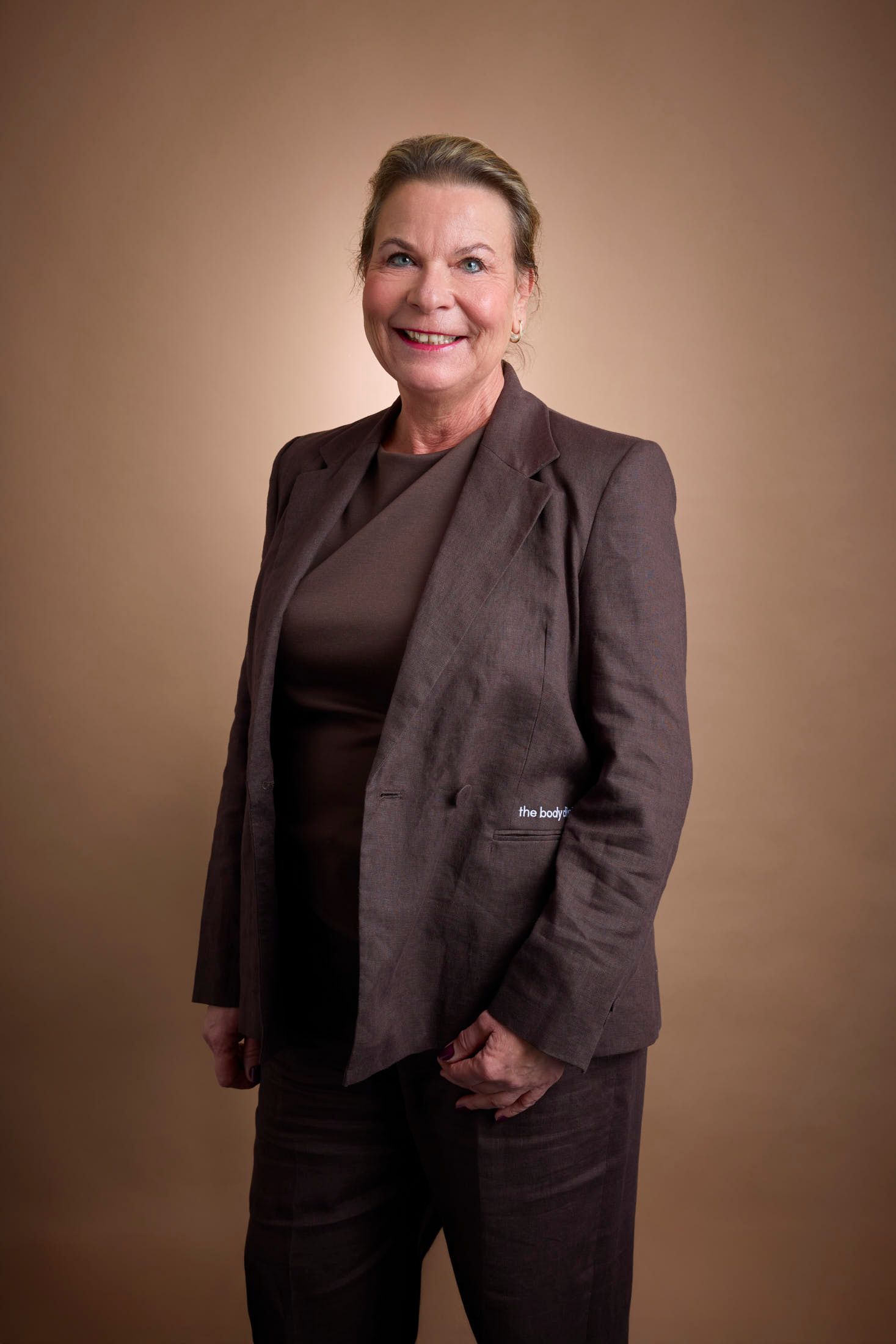Smiling professional woman in a dark suit with short hair, looking confidently at the camera.