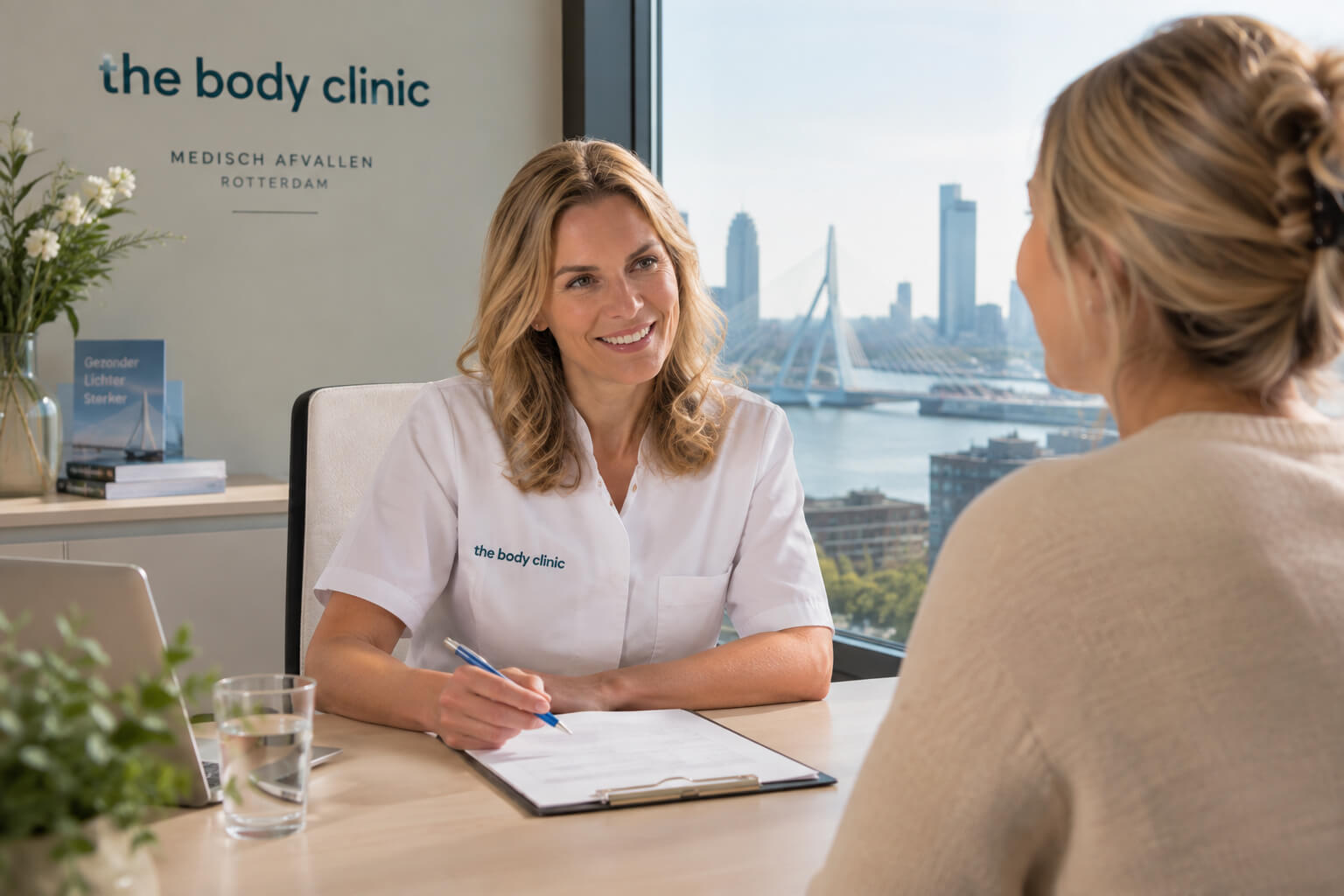 A female clinician smiles while consulting a patient at her desk with a city view.