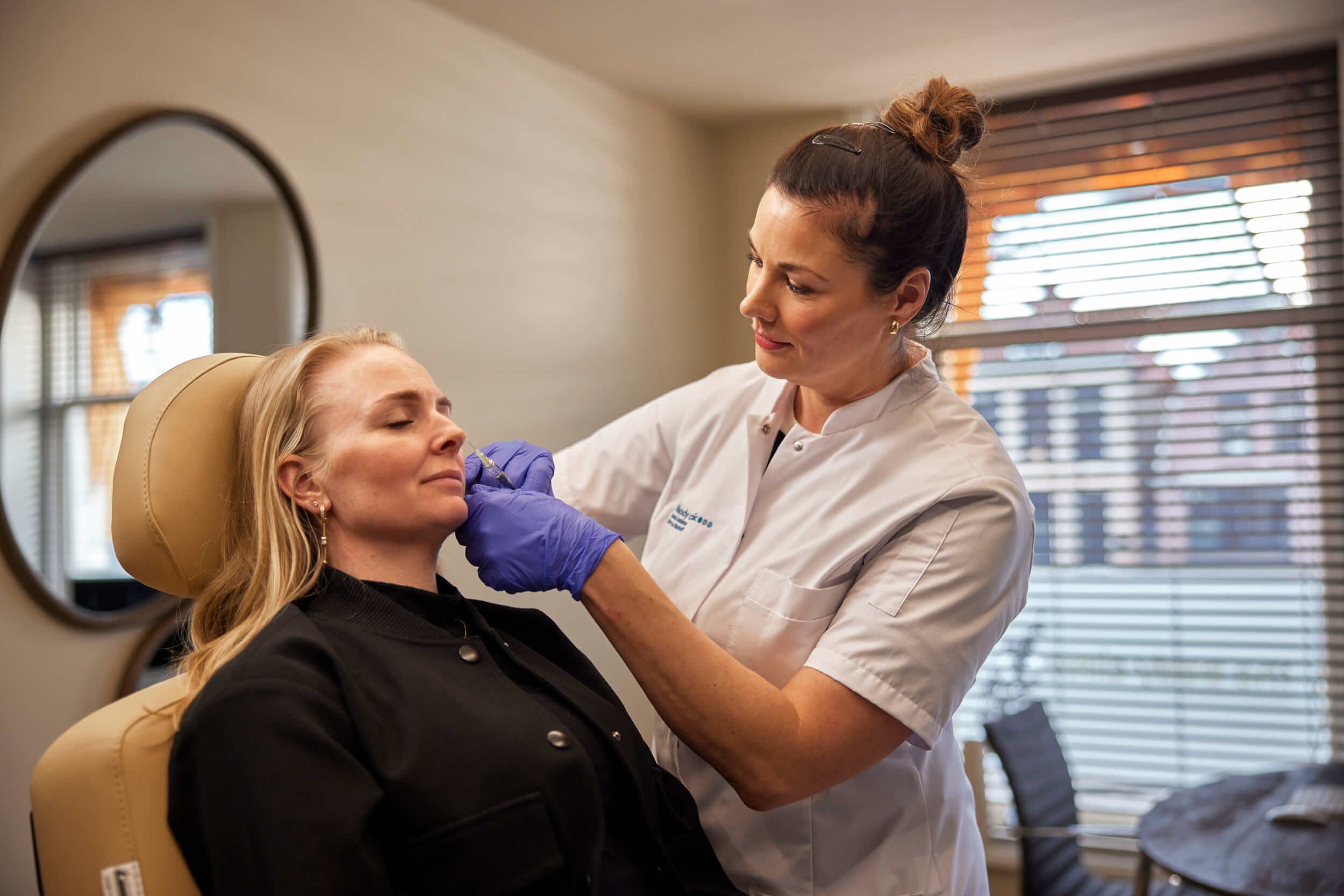 Cosmetisch arts voert traangootbehandeling uit tegen wallen met client bij The Body Clinic
