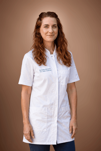Professional woman with red hair in white lab coat smiles gently.