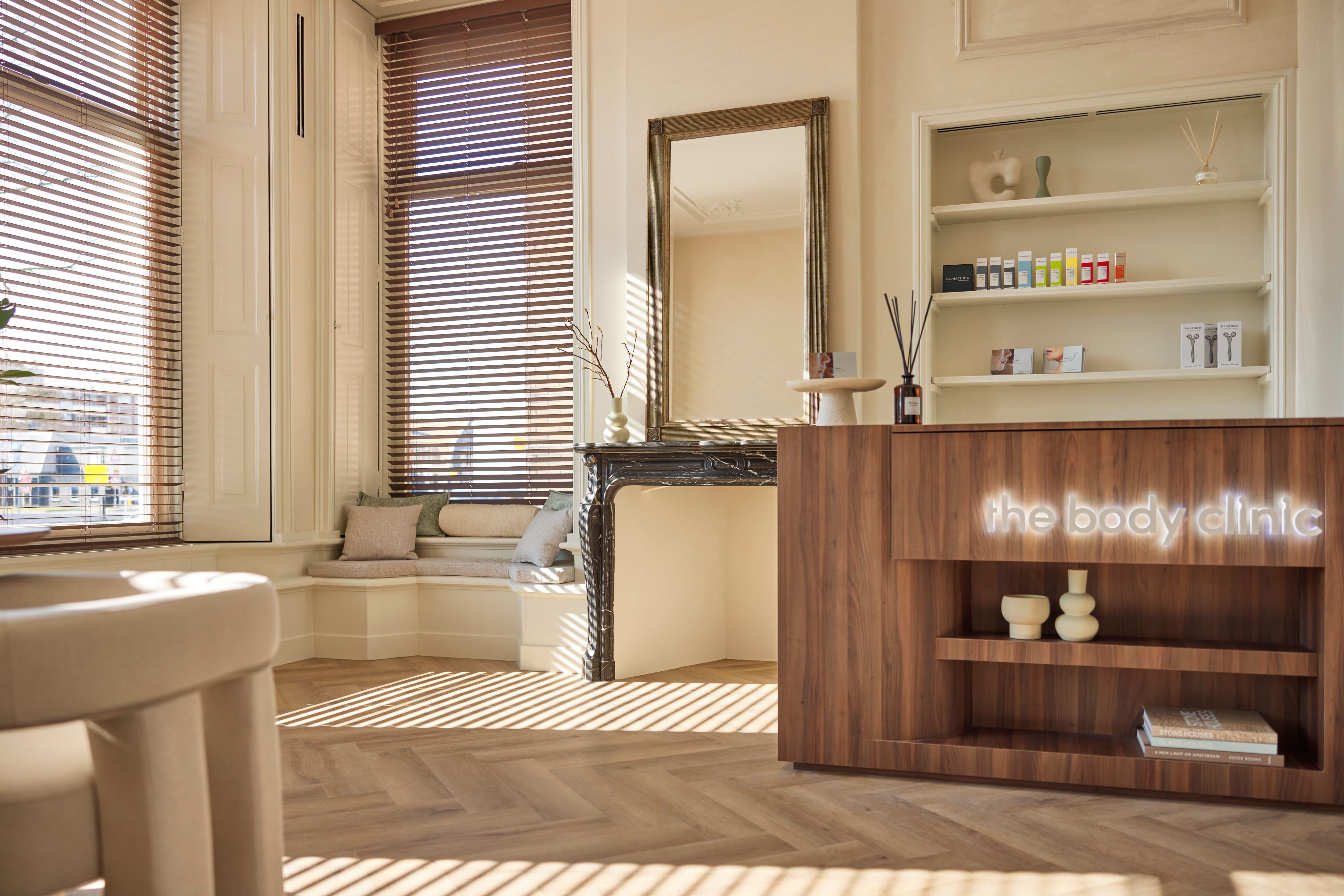 Stijlvolle receptie en wachtruimte van een The Body Clinic kliniek met warme natuurlijke materialen