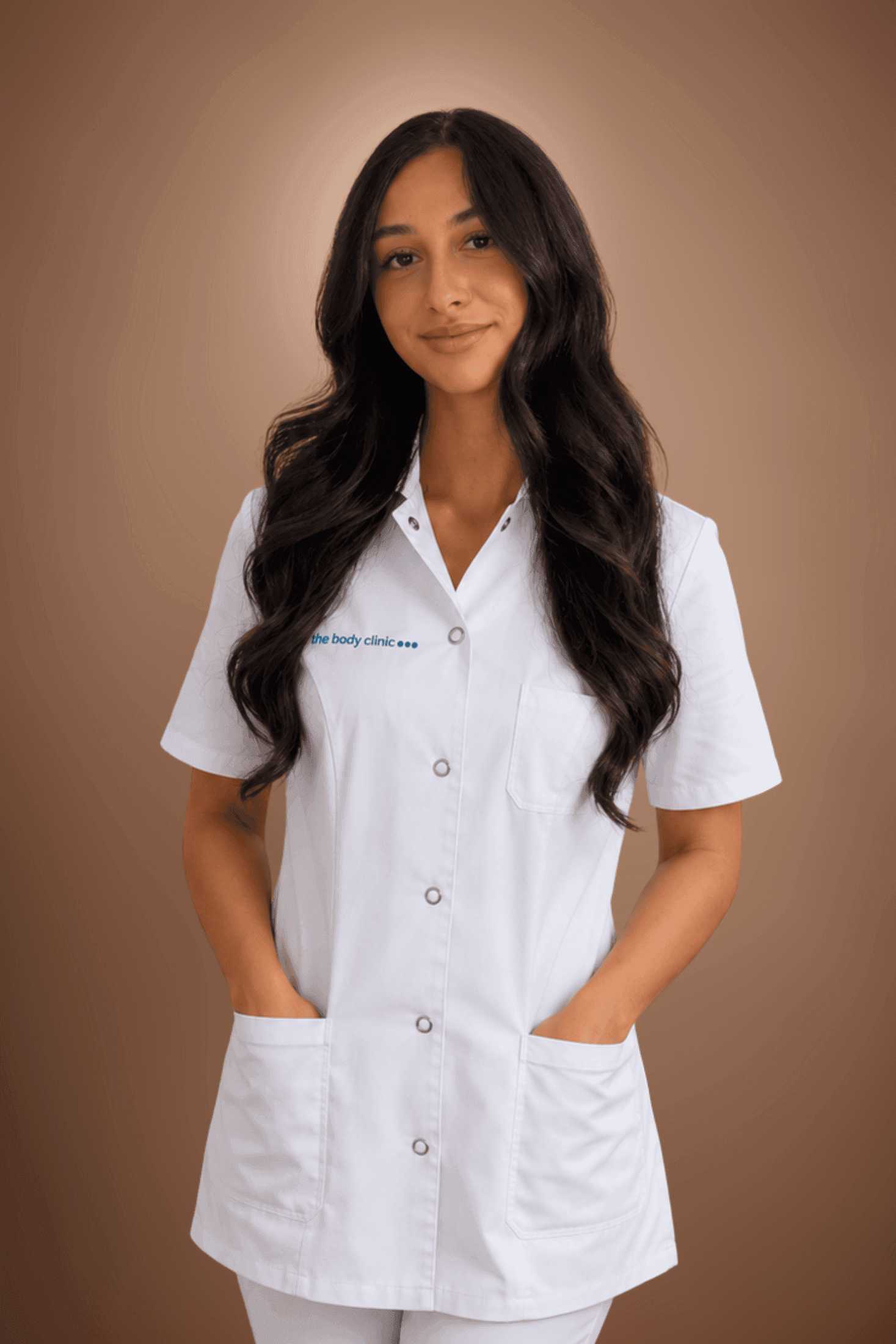 Young woman in a white medical uniform with dark wavy hair smiling.