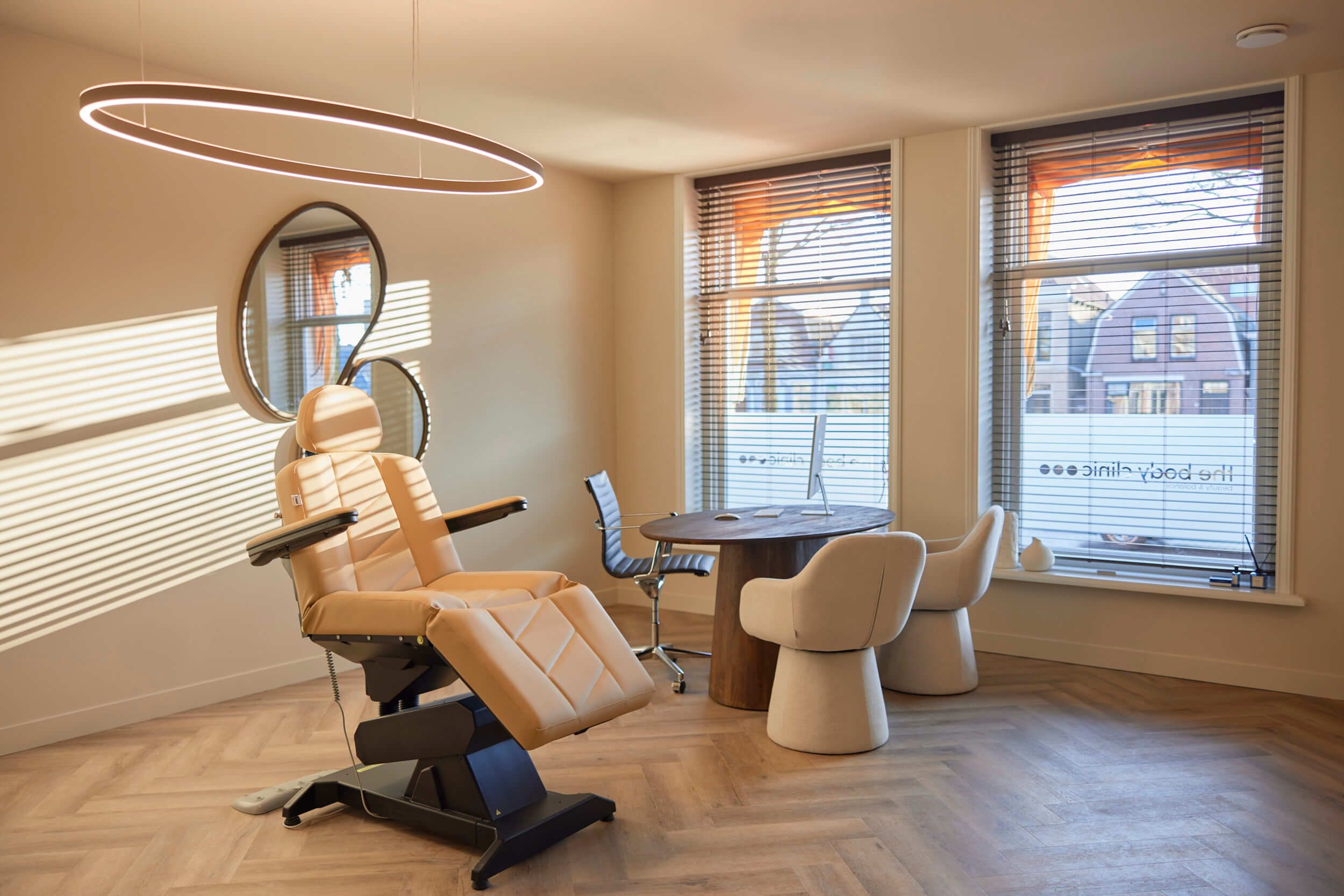 Moderne behandelkamer met behandelstoel en consultatie tafel bij The Body Clinic