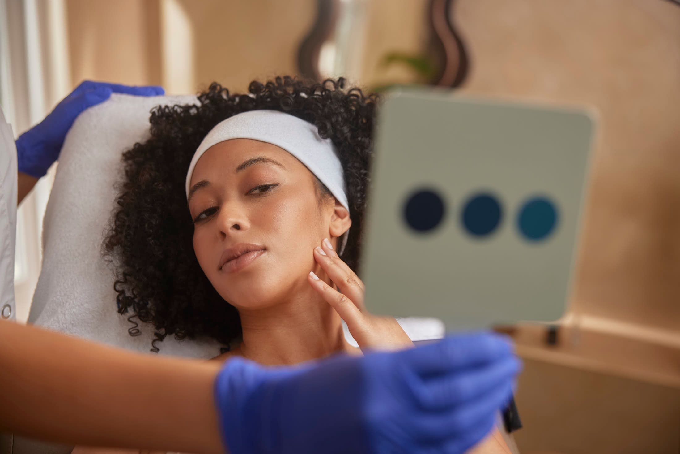 Client bekijkt resultaat in spiegel terwijl huidtherapeut de huid beoordeelt na HIFU behandeling bij The Body Clinic