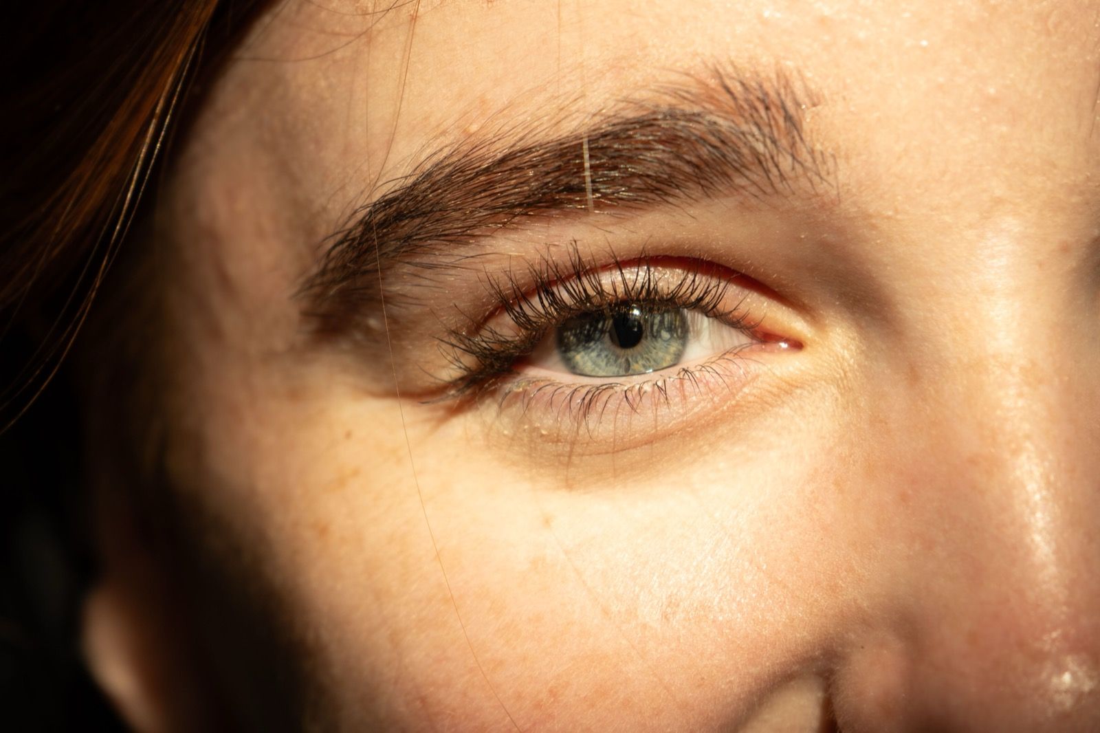 Close-up of a bright blue eye with long eyelashes and a well-defined eyebrow.