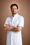Man in white medical coat with crossed arms and a slight smile.