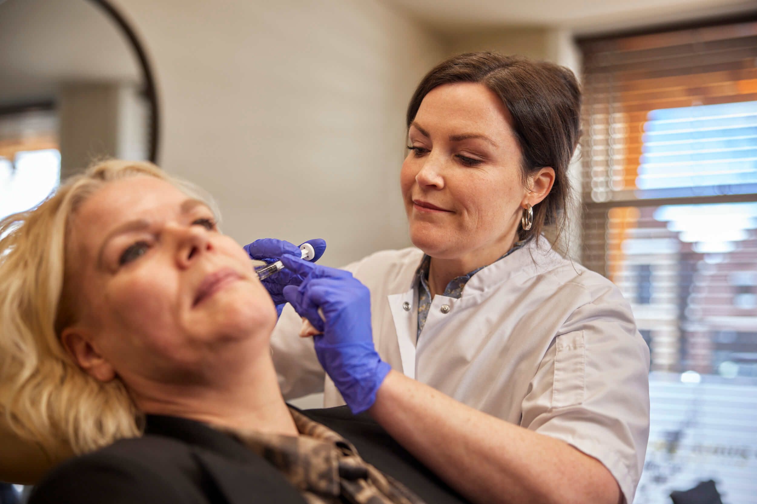 Cosmetisch arts voert behandeling met injectables uit bij client met aandacht en zorg bij The Body Clinic