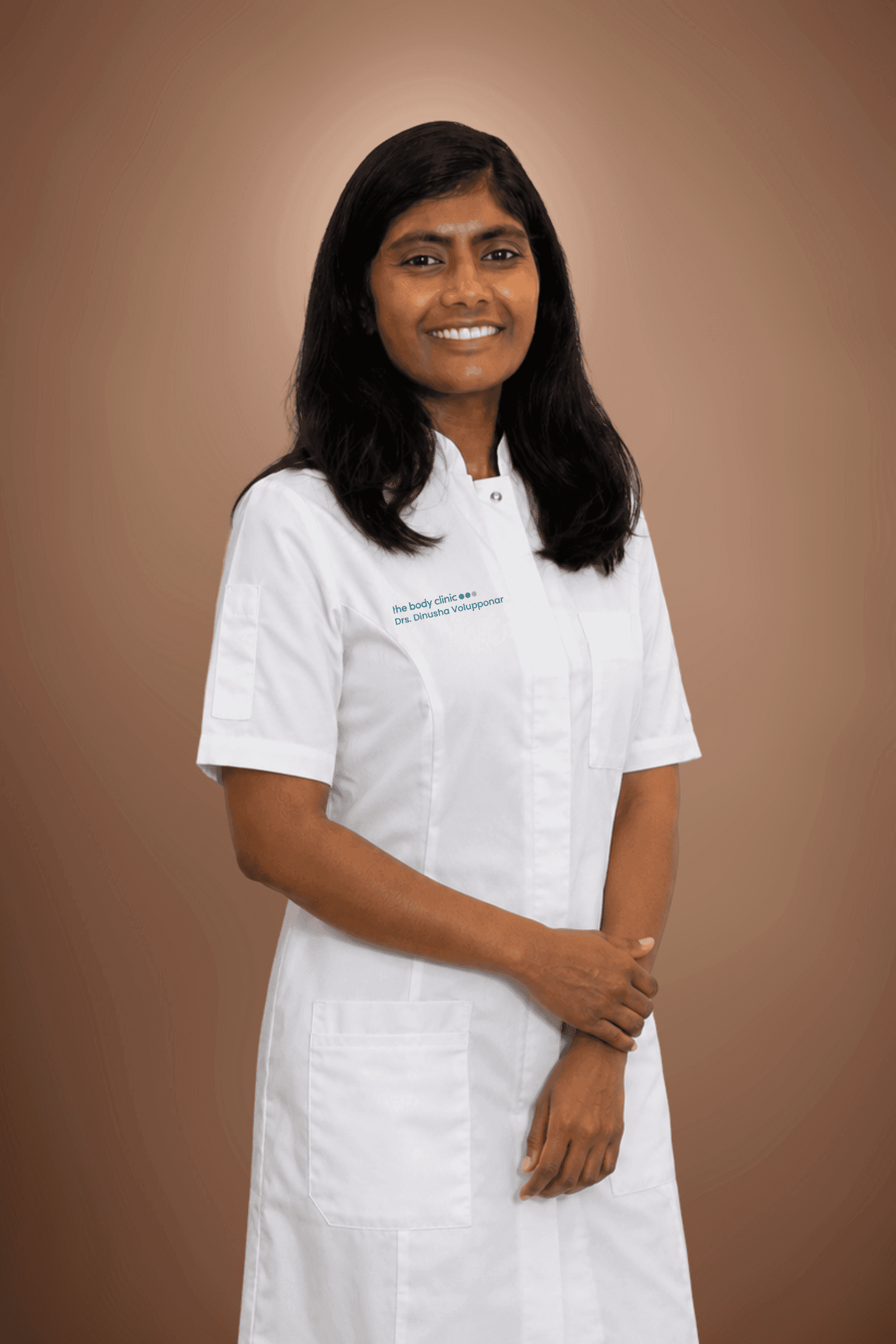 A smiling woman in a white lab coat with crossed arms poses professionally.