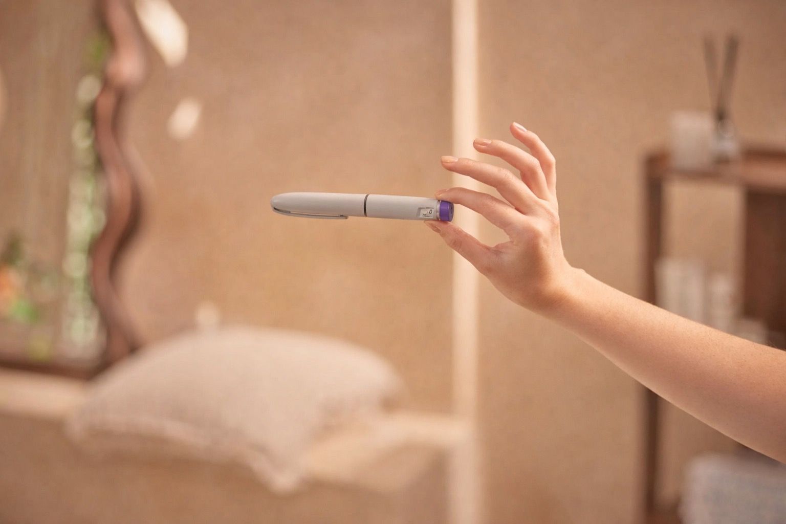 A hand holds a pregnancy test horizontally in a blurred bathroom setting.