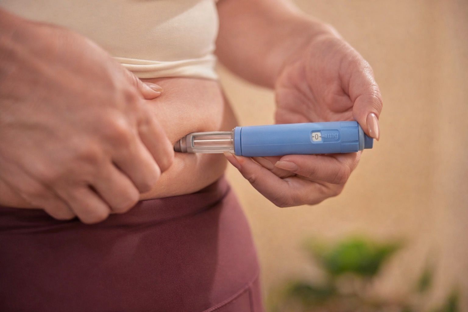 Person self-injecting medication into their abdomen with a blue auto-injector pen.