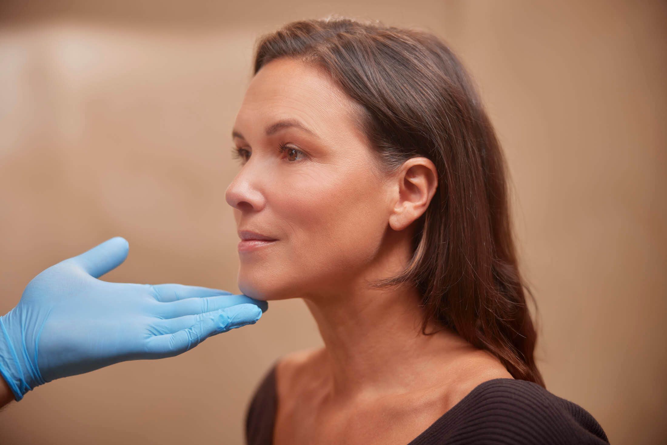 Huidtherapeut bekijkt de huidconditie van een vrouw om te bepalen bij welke huidproblemen een Rejuran behandeling geschikt is