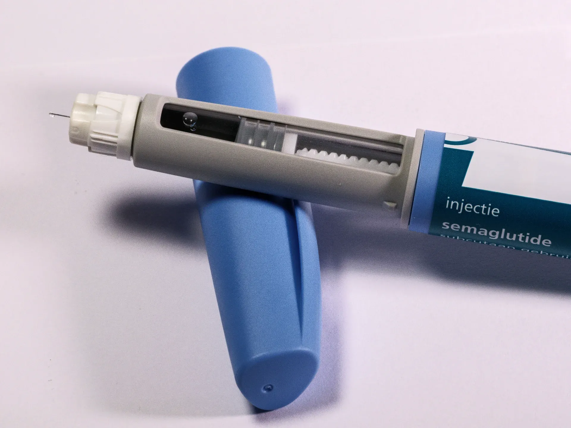 Blue and gray injection pen with a needle, labeled for semaglutide, used for medication delivery.