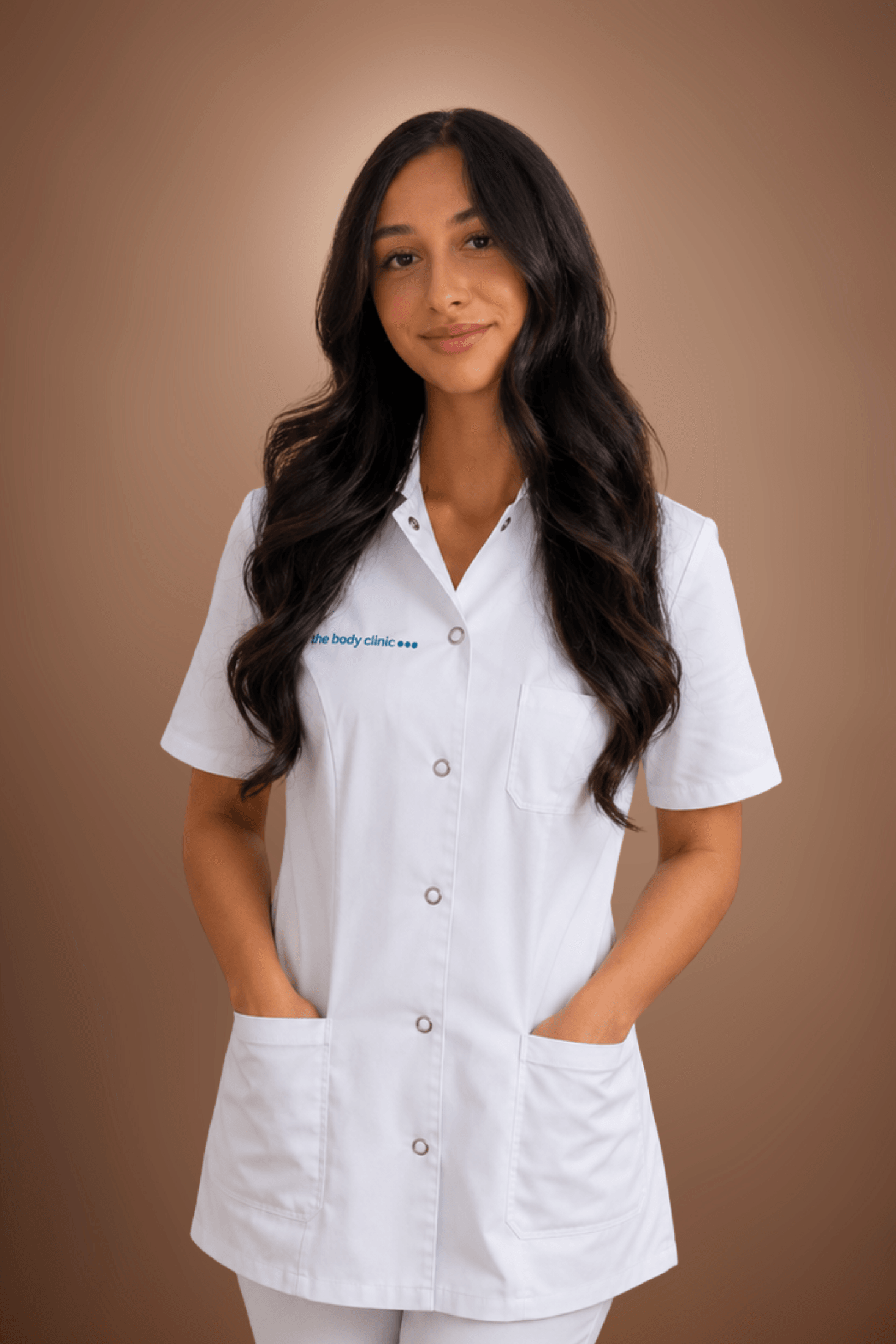 Young woman with dark hair wearing a white medical uniform, hands in pockets.