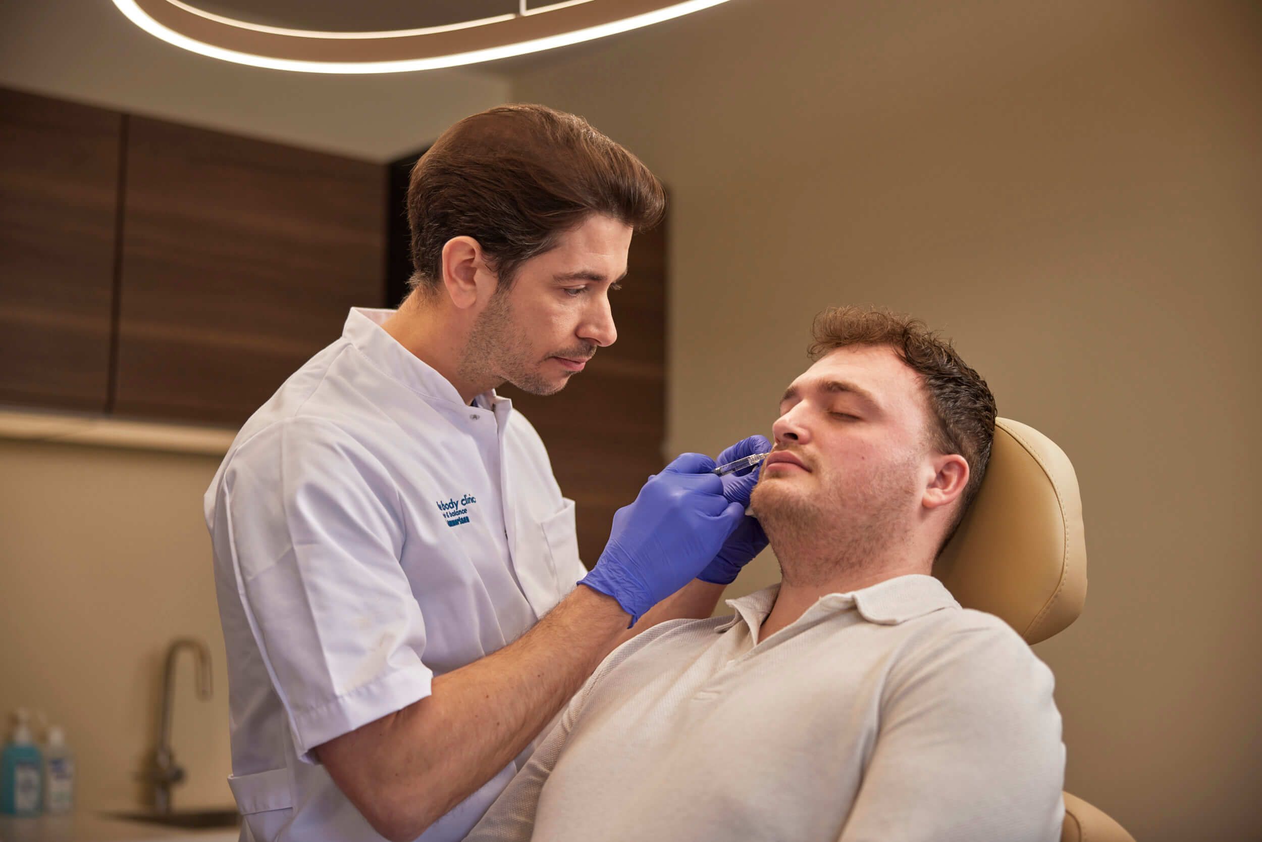 Cosmetisch arts voert traangootbehandeling uit tegen wallen met client bij The Body Clinic